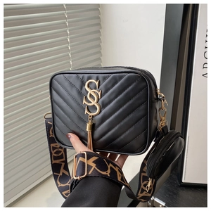 Detail of black quilted crossbody bag with golden SS logo, tassel and jacquard strap