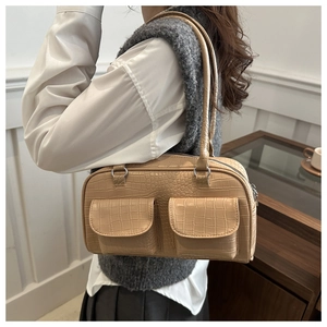 Detail view of light brown crocodile pattern shoulder bag with two front flap pockets