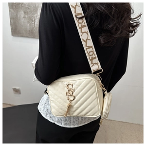 Detail of quilted beige camera bag with wide lettered strap and small round pouch