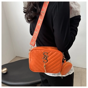 Detail of orange quilted crossbody bag with lucky jacquard strap and mini round purse