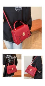 Detail of red crossbody bag featuring a golden circular twist lock and side metal zippers