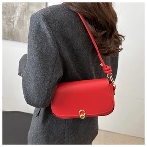 Close-up of red saddle bag with gold metal buckle and knotted strap on grey blazer