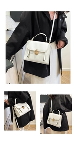 Close-up of white leather handbag with golden twist lock and vertical zipper detail