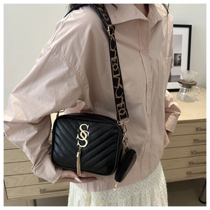 Detail of black chevron quilted camera bag with gold hardware, tassel and wide strap