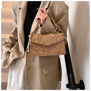Detail of beige square bag with lotus koi relief and woven handle on stylish model