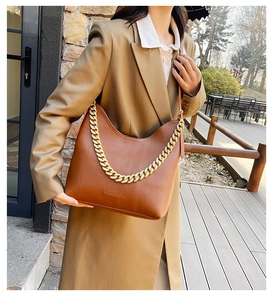 Dettaglio borsa hobo in pelle martellata marrone con catena dorata indossata da modella