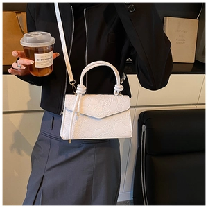 Detailed view of white floral embossed leather bag with knotted handle and gold metal hardware