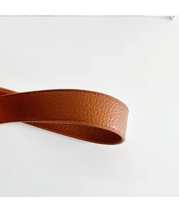 Dettaglio della tracolla in pelle martellata marrone con cuciture precise su una borsa