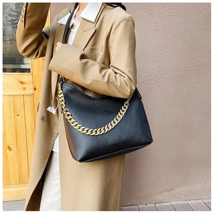 Dettaglio borsa hobo in pelle nera a grana litchi con spessa catena dorata sul modello