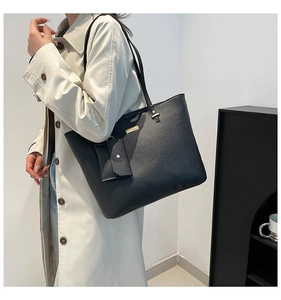 Detail of black tote bag featuring textured leather and a matching envelope pouch