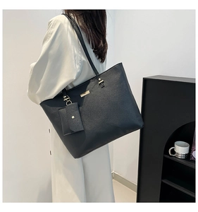 Detail of black pebbled leather tote bag with gold hardware and small coin purse attached