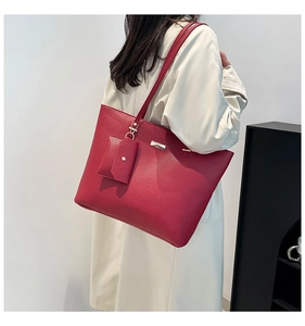 Detailed view of red pebble leather tote bag with matching pouch and gold hardware