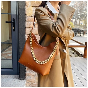 Dettaglio borsa tote in pelle marrone con catena in metallo e logo stampato in oro