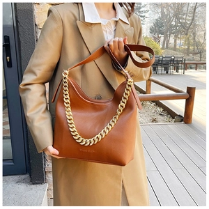 Dettaglio della borsa in pelle marrone con catena dorata spessa e logo impresso