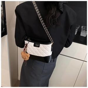 Détail du sac à bandoulière matelassé noir et blanc avec breloque d'ours peluche