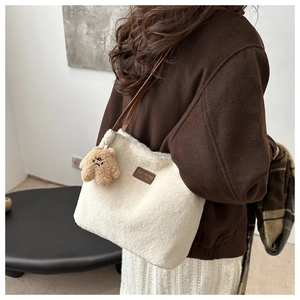 Détail d'un sac seau en peluche blanche avec bandoulière et breloque ours mignon