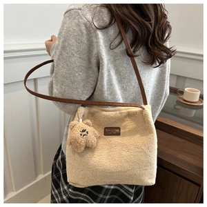 Détail du sac fourre-tout en peluche beige avec bretelles brunes et pendentif d'ours