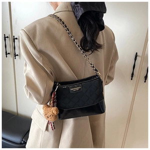 Détail du sac matelassé noir avec base en cuir verni et breloque ours mignon