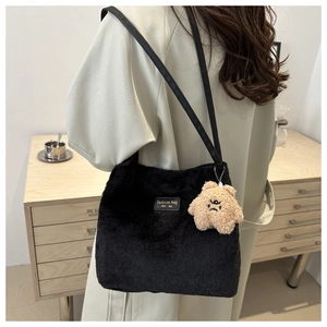 Détail d'un sac cabas en peluche noire avec texture fausse fourrure et breloque d'ours