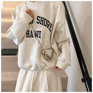 Detail of silver heart-shaped crossbody box bag with metal chain on a casual outfit