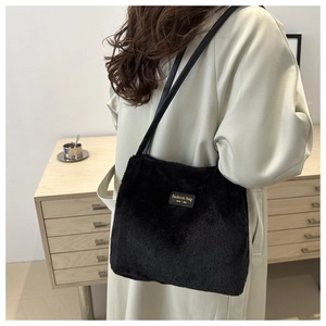 Detail of plush black tote bag with gold-embossed leather label and long handles