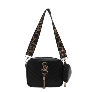 Black V-quilted crossbody bag with gold logo, fringe tassel, and wide jacquard strap