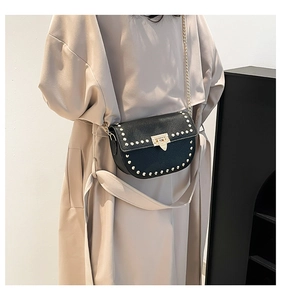 Detail of black pebbled leather crossbody bag with gold studs and chain strap