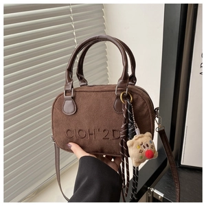 Detail of dark brown matte suede bowling bag with logo embossing and a cute bear charm