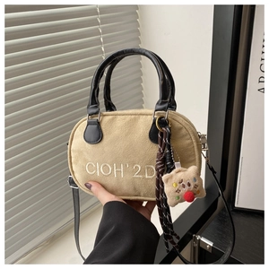 Detail of beige suede crossbody bag with white embroidery and a cute bear charm