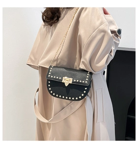 Détail d'un sac bandoulière en cuir noir avec clous dorés et bandoulière en chaîne
