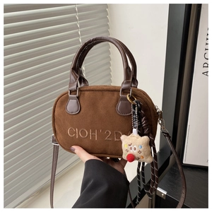 Detail of brown faux suede bowling bag with star plush charm and letter embroidery