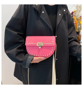 Detailed shot of fuchsia saddle bag with gold studs, lychee grain leather, and chain strap