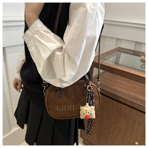 Detail der braunen Vintage-Wildledertasche mit Plüsch-Anhänger und kariertem Tuch