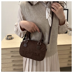 Retro brown suede bowling bag with embossed letters shown on model in warm setting
