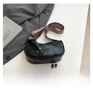 Black vintage pillow bag with woven strap shown next to a smartphone for size reference