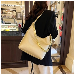 Borsa hobo in pelle martellata champagne con grossa catena dorata indossata sulla spalla