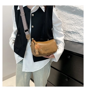Brown leather crossbody pillow bag featuring a stylish black and white geometric woven strap
