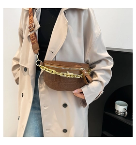 Detailansicht der braunen Brusttasche mit Krokostruktur, Goldkette und bedrucktem Gurt