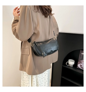 Minimalist black matte crossbody moon bag styled with a brown blazer and white polka dot skirt