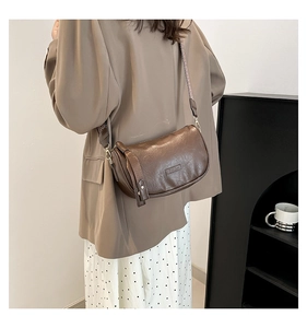 Detail of coffee-colored pleated shoulder bag with wide geometric jacquard strap and metal hooks