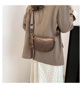 Detail of a brown leather crossbody bag with geometric wide strap and gold hardware