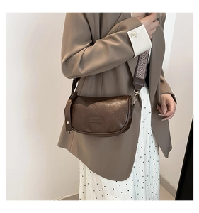 Detail view of coffee PU saddle bag with patterned jacquard strap and gold hardware