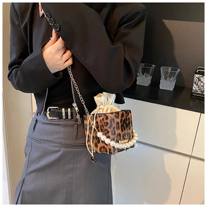 Detalle del bolso de leopardo con asa de perlas, cadena metálica y cierre de cordón