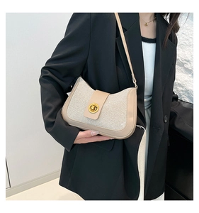 Detail of beige leather and tweed patchwork underarm bag with gold circular clasp