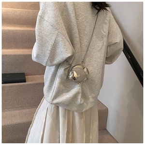 Detail of silver fish-shaped crossbody bag with metallic scale texture and chain strap