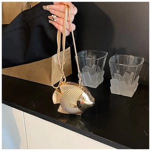 Detail of fish-shaped gold metal mini bag featuring scale texture and snake chain