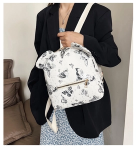 Detail showing white backpack with black butterfly print and golden zipper hardware