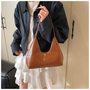 Close-up of a brown leather hobo bag with a silver zipper and elegant shoulder strap