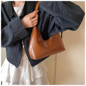 Dettaglio borsa hobo in pelle marrone con piedini metallici e logo del marchio inciso