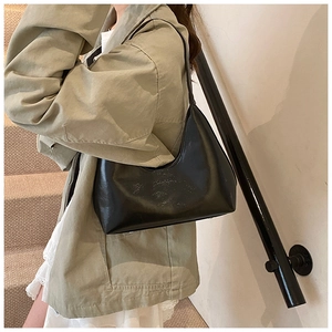 Detail of minimalist black leather underarm bag with smooth texture on a model shoulder